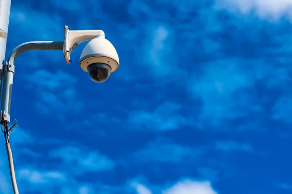 Security camera on a pole against blue sky background.