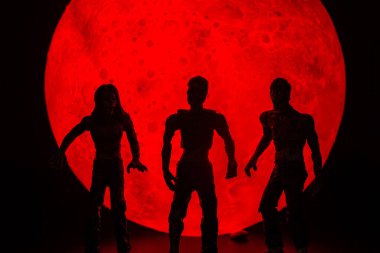 The silhouette of Halloween zombies decorations.There's a red full moon in the background. Halloween horror concept. clipart