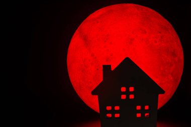 The silhouette of a Horror haunted house. There's a red full moon in the background. Halloween horror concept. clipart
