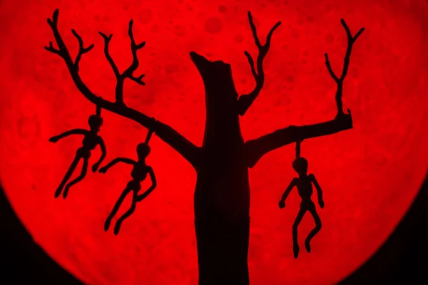 男と死んで立っている木のシルエットは 骨に死者を絞首刑にした 背景に赤い満月があります ハロウィンホラーのコンセプト — ストック写真