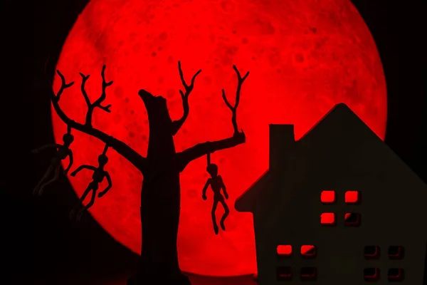男と死んだ立っている木のシルエットは 骨やホラーお化け屋敷に死者を絞首刑にしました 背景に赤い満月があります ハロウィンホラーのコンセプト — ストック写真