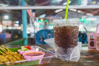 Tayland 'da yüzen pazarlarda yiyecek ve içecekler ahşap masalarda.