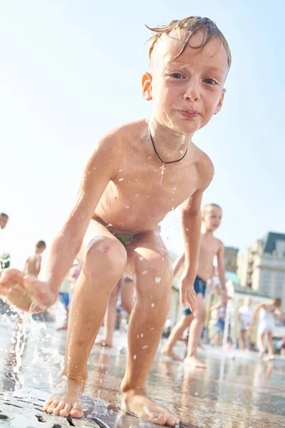 小男孩沐浴在城市喷泉里溅起水花 — 图库照片