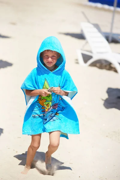 穿着毛巾的男孩沿着沙滩走着 收集贝壳 — 图库照片