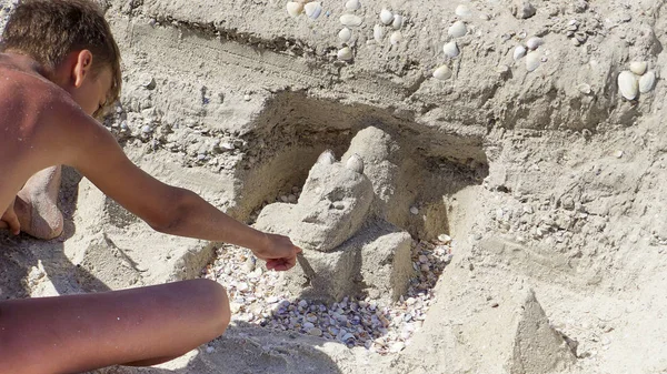 少年ティーンは海岸の砂からロックを構築し シェルで飾られました — ストック写真