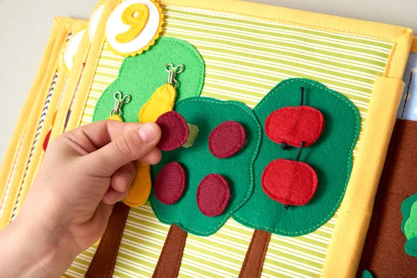 Barnens textil lärobok. Baby leker i en trädgård med frukter — Stockfoto