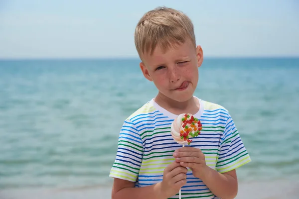 Kleiner Junge isst am Strand Süßigkeiten — Stockfoto