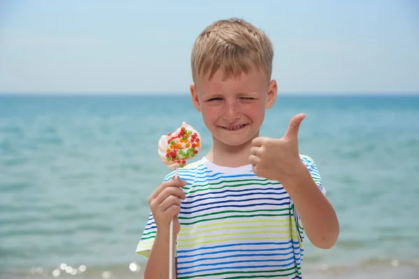 Rapaz pequeno que come na praia doce doces — Fotografia de Stock