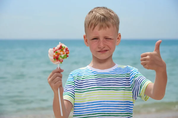 Küçük oğlan yeme üzerinde the plaj tatlı Candy — Stok fotoğraf