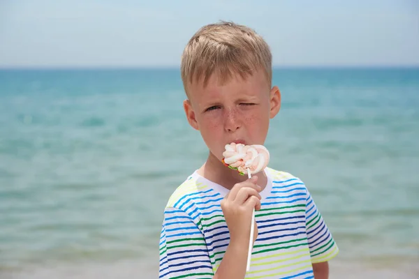 Маленький мальчик, питающийся на пляже сладкой сладостью — стоковое фото