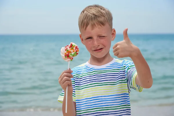 Rapaz pequeno que come na praia doce doces — Fotografia de Stock