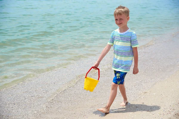 EL NIÑO SE VA CON UN BUCKET EN LA PLAYA DE SANDY DEL MAR — Foto de Stock