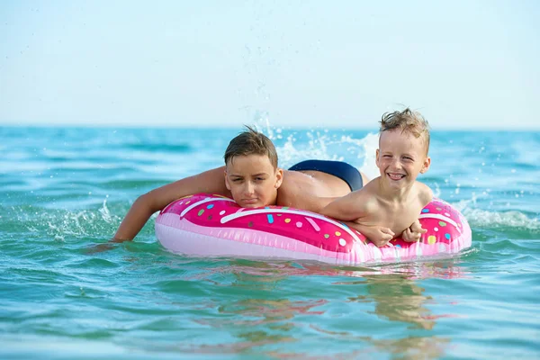 DOS NIÑOS AHORRA EN UN CÍRCULO INFLATABLE EN EL MAR — Foto de Stock