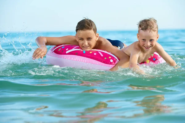 TWO BOYS SAVE ON A INFLATABLE CIRCLE AT SEA — Stock Photo, Image