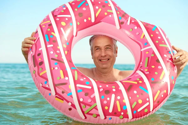 Gris de pelo divertido hombre nada en un círculo inflable en el mar — Foto de Stock