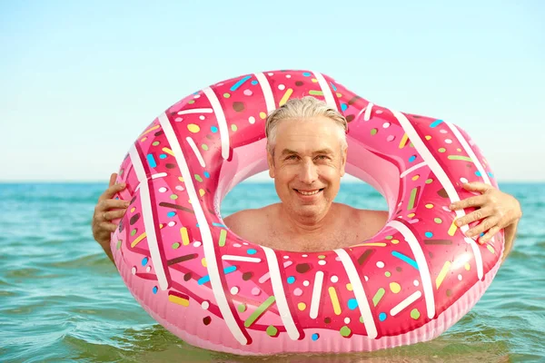 Gris de pelo divertido hombre nada en un círculo inflable en el mar — Foto de Stock