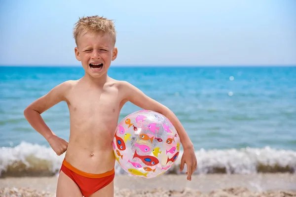 Menino 7 anos com bola inflável na praia perto do mar — Fotografia de Stock