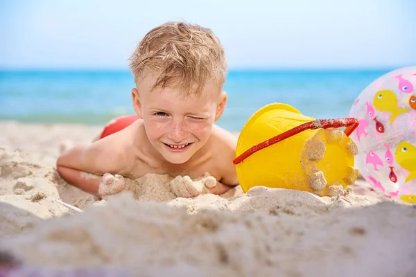 LITTLE BOY LIES ON A SEA SANDY BEACH. — Stock Photo, Image