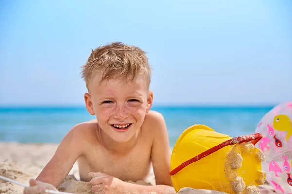 Niño se encuentra en una playa de arena de mar. — Foto de Stock