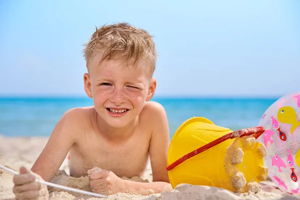 LITTLE BOY LIES ON A SEA SANDY BEACH. — Stock Photo, Image
