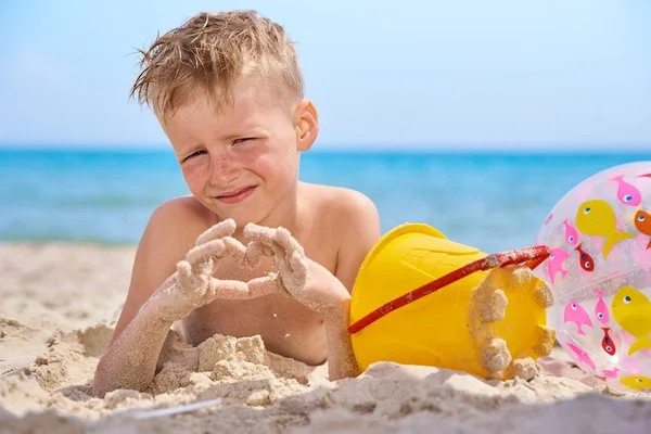 LITTLE BOY LIES ON A SEA SANDY BEACH. — Stock Photo, Image