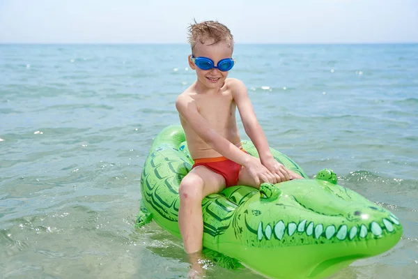 BOY SWIMS NO MAR NO CROCODYLE TOY INFLATÁVEL . — Fotografia de Stock