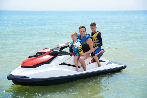 FAMILY FATHER WITH SONS ON A HYDROCYCLE IN THE SEA — Stock Photo, Image