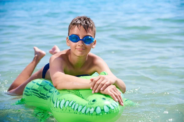 Niño de adolescentes con gafas de agua nada en el juguete inflable CROCODILE. . — Foto de Stock