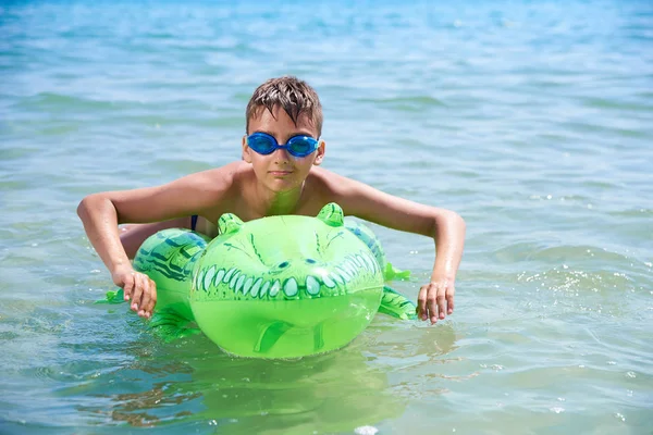 Niño de adolescentes con gafas de agua nada en el juguete inflable CROCODILE. . — Foto de Stock