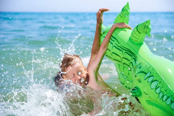 BOY OF TEENAGERS IN WATER GOGGLES SWIMS ON THE INFLATABLE TOY CROCODILE. — Stock Photo, Image