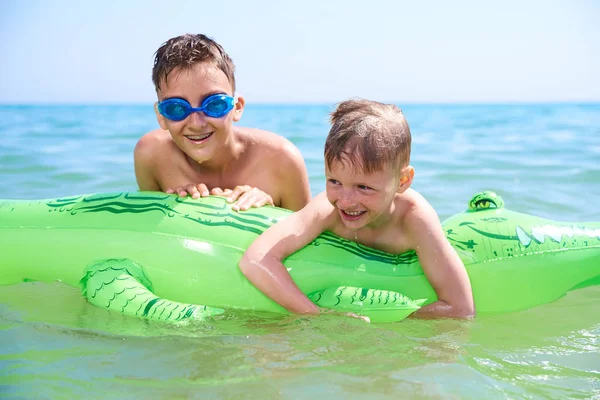 Niño de adolescentes con gafas de agua nada en el juguete inflable CROCODILE. . — Foto de Stock