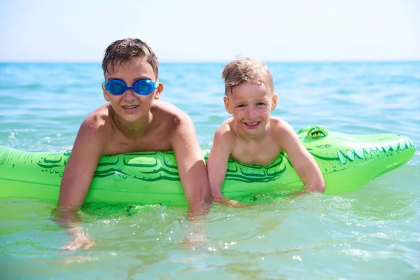 Niño de adolescentes con gafas de agua nada en el juguete inflable CROCODILE. . — Foto de Stock