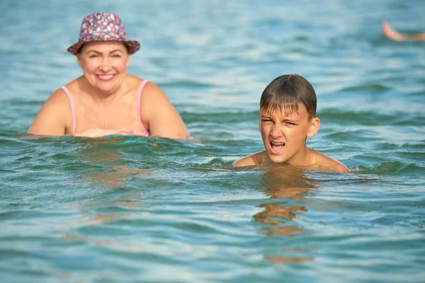Grandmother and grandson swim together in the se