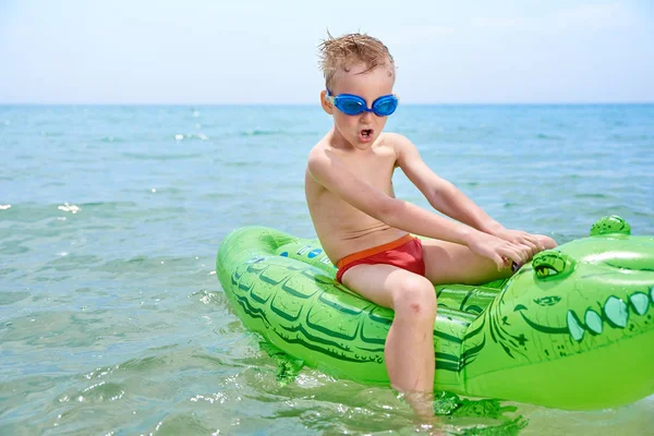 BOY SWIMS NO MAR NO CROCODYLE TOY INFLATÁVEL . — Fotografia de Stock