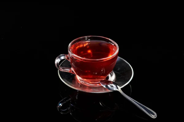 Copa de vidrio con té rojo caliente sobre un fondo negro . — Foto de Stock