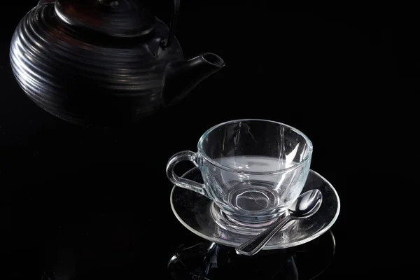 Chá quente vermelho é derramado a partir do bule em uma xícara de vidro em um fundo preto — Fotografia de Stock
