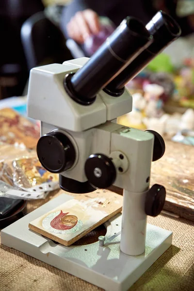 Der Künstler malt eine religiöse Miniatur-Ikone der Jungfrau Maria durch ein Mikroskop. — Stockfoto