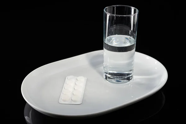 黒の背景に白い板の上に水と薬のガラス. — ストック写真