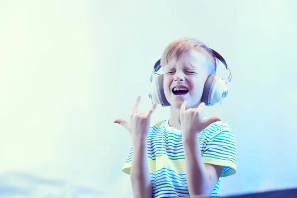 ヘッドフォンの面白い少年は音楽を聞いて歌を歌う — ストック写真