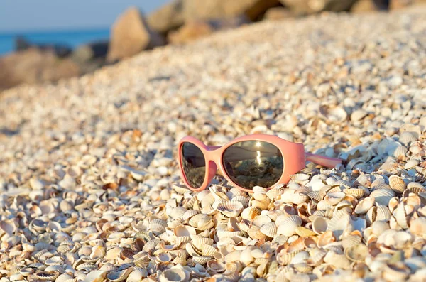 children\'s sunglasses on the seashore shells