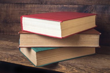 ahşap bir rafa yığılmış üç eski kitap