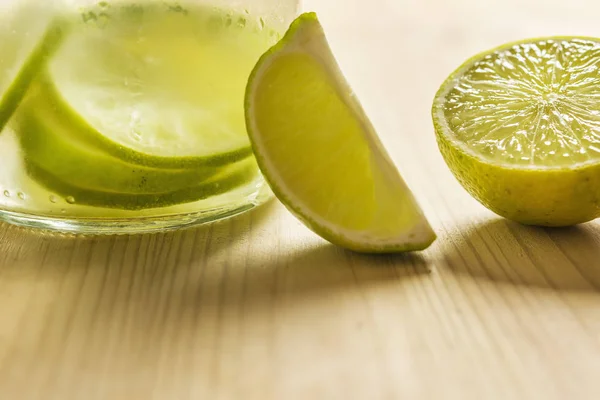 Lemon soda and pieces of lime on wooden table — Stock Photo, Image