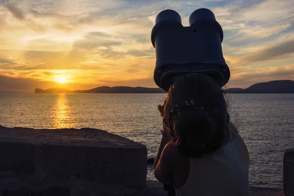 Bambina che guarda attraverso un binocolo al tramonto — Foto Stock