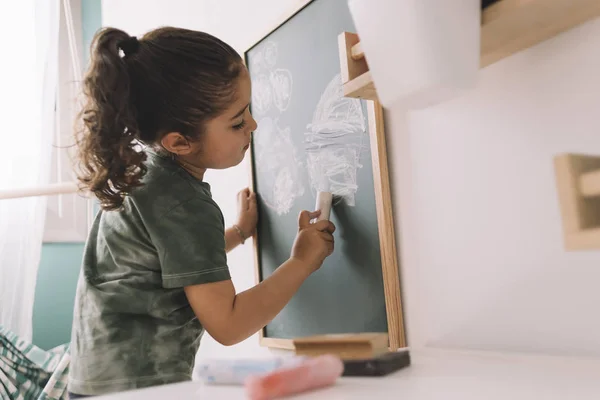 Petite fille dessinant sur un tableau dans sa chambre — Photo