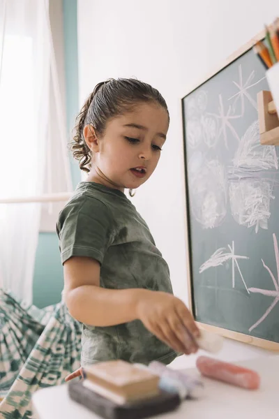 Petite fille prend une craie pour continuer à dessiner — Photo