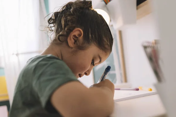 Petite fille écrit concentré au bureau — Photo