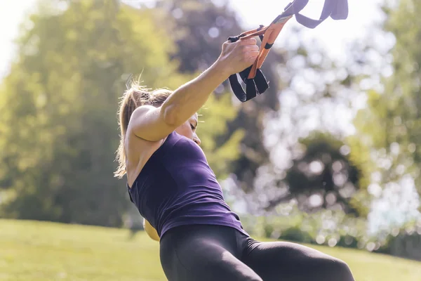 Mulher treinando ao ar livre com tiras de suspensão — Fotografia de Stock