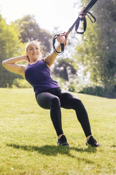 fitness woman that smiles training with straps