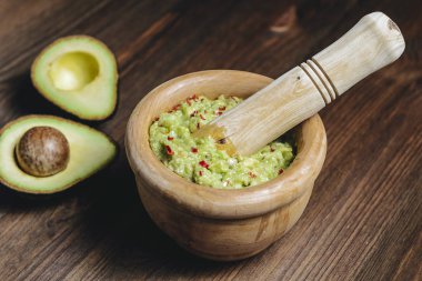 ahşap bir kase guacamole ve yarım avokado kesilmiş