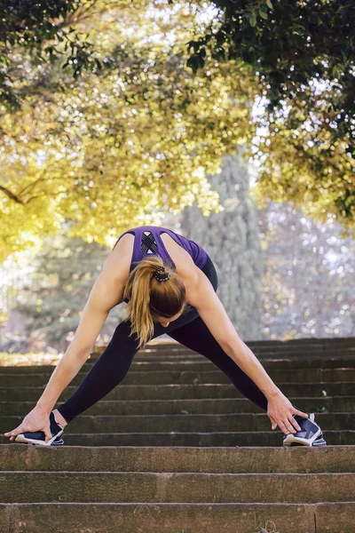 Mulher corredor esticando pernas antes de correr — Fotografia de Stock